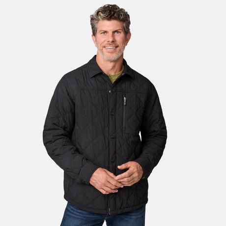 [Kolby is 6'2" wearing size M.] Men’s Free Country black quilted jacket with diamond pattern stitching—featuring button front closure, zippered left chest pocket, and side hand pockets. Layered over a green crewneck tee and blue jeans for a laid-back, outdoors-ready aesthetic.
