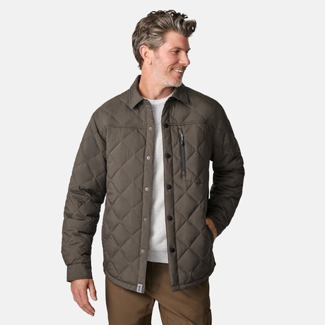 [Kolby is 6'2" wearing size M.] Men’s Free Country quilted jacket in brown with diamond pattern stitching—features a zippered left chest pocket, button front closure, and side hand pockets. Styled over a light gray shirt and paired with brown pants for a rugged, polished outdoor look.