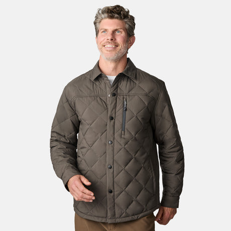 [Kolby is 6'2" wearing size M.] Men’s Free Country quilted jacket in brown with diamond pattern stitching—features a zippered left chest pocket, button front closure, and side hand pockets. Styled over a light gray shirt and paired with brown pants for a rugged, polished outdoor look.
