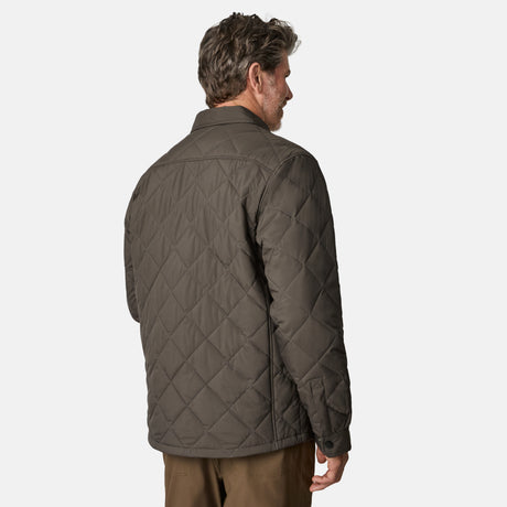 [Kolby is 6'2" wearing size M.] Men’s Free Country quilted jacket in brown with diamond pattern stitching—features a zippered left chest pocket, button front closure, and side hand pockets. Styled over a light gray shirt and paired with brown pants for a rugged, polished outdoor look.