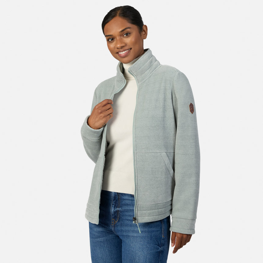 [Model is wearing size S.] A woman modeling a light green heather zip-up fleece jacket with a mock neck collar, paired with blue jeans, against a plain light gray studio background.