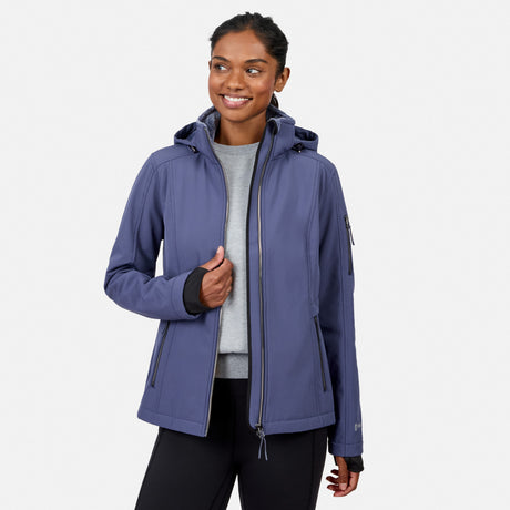 [Model is wearing size S.] A woman wearing a slate blue hooded softshell jacket over a gray top and black pants, standing against a light gray studio background.