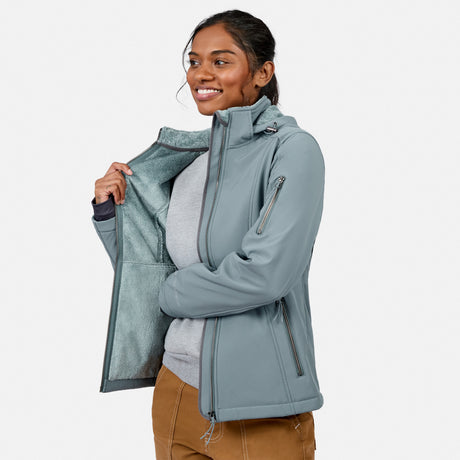 [Model is wearing size S.] A woman wearing a slate blue-gray softshell jacket with a fleece-lined interior, shown against a light gray studio background.