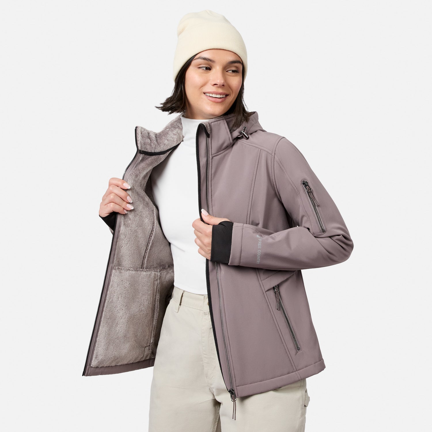 [Model is wearing size S.] A woman wearing a light taupe hooded jacket with black trim, a cream beanie, and light beige pants, shown against a plain light gray studio background.