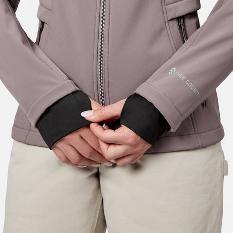 [Model is wearing size S.] Close-up of a person wearing a taupe Free Country jacket with black ribbed cuffs and light beige pants, hands clasped in front.