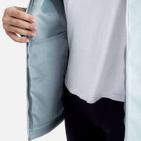 A person in a white shirt and black pants holds open a light blue Clearance Women's Anorak Softshell Jacket, revealing its soft, matching inner lining and an interior pocket.