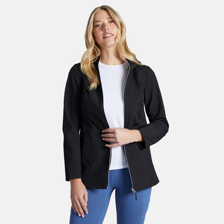 A woman with long blonde hair wears the Clearance Women's Anorak Softshell Jacket over a white shirt and blue pants, standing against a plain white background and smiling softly at the camera.