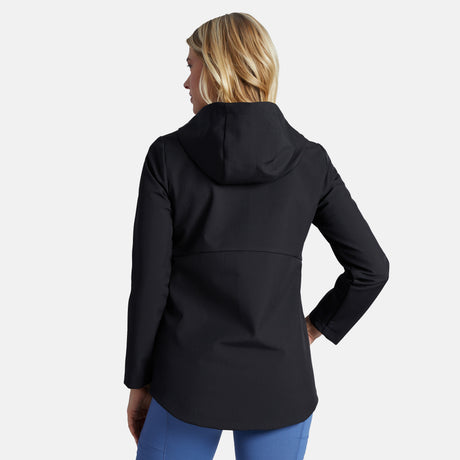 A woman with blonde hair is seen from behind, modeling the Clearance Women's Anorak Softshell Jacket in black with blue pants, against a plain light gray background.