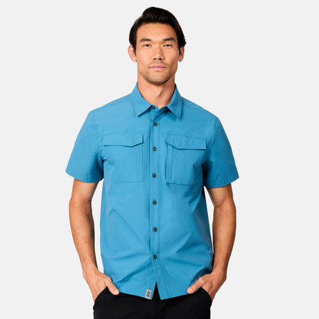 [Scott is 6’3 wearing size M] Man wearing a blue short-sleeve button up shirt on a white background