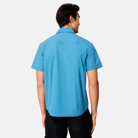 [Scott is 6’3 wearing size M] Man wearing a blue short-sleeve button up shirt on a white background