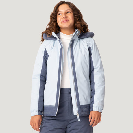 [Model is wearing a size Medium.] Girl wearing the Free Country Girls' Boarder Jacket in light blue and navy, featuring Butter Pile® lining, a wind- and water-resistant shell, and a hooded design, paired with matching navy snow pants.