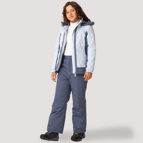 [Model is wearing a size Medium.] Girl wearing the Free Country Girls' Boarder Jacket in light blue and navy, featuring Butter Pile® lining, a wind- and water-resistant shell, and a hooded design, paired with matching navy snow pants.