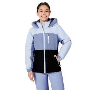 A young girl smiling while wearing a color-blocked hooded ski jacket in light blue, lavender, and black, paired with matching light blue pants, against a solid white background.