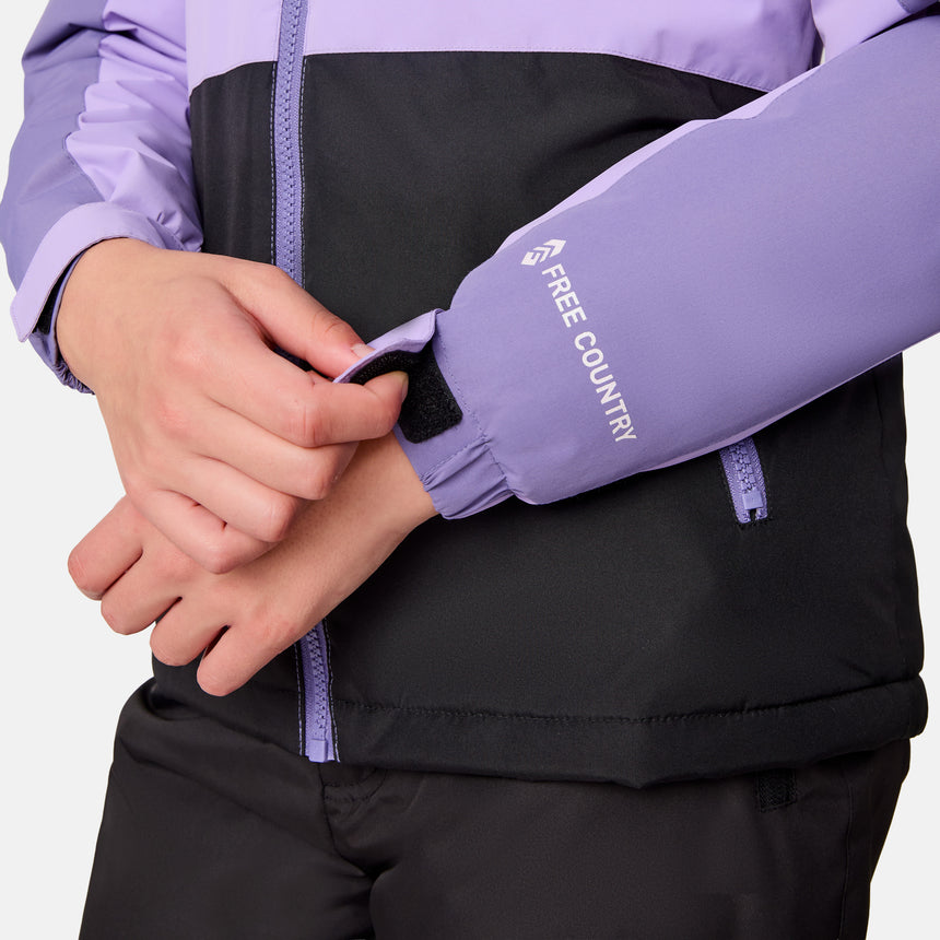 [Samantha is wearing size M.] Close-up of a person wearing a purple jacket with 'Free Country' branding, focusing on the sleeve and hand.