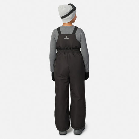 Back view of a child wearing black Free Country ski bib pants over a gray long sleeve shirt and a gray knit beanie.
