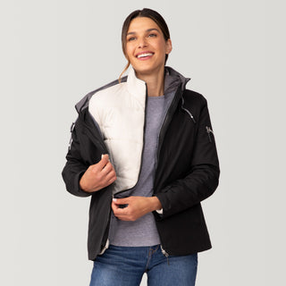 [Olga is 5’9” wearing a size Small.] Woman wearing Free Country Women's Back of Bell 3-in-1 Systems Jacket in black with a full front zipper opening, soft lining, attached hood with adjustable drawcords, and water resistant and wind resistant stretch performance fabric, inner puffer jacket, outer shell for weather, light grey background. Perfect women’s  jacket for fall weather.