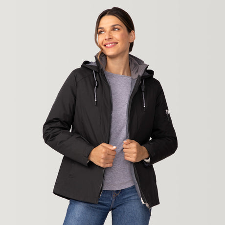 [Olga is 5’9” wearing a size Small.] Woman wearing Free Country Women's Back of Bell 3-in-1 Systems Jacket in black with a full front zipper opening, soft lining, attached hood with adjustable drawcords, and water resistant and wind resistant stretch performance fabric, inner puffer jacket, outer shell for weather, light grey background. Perfect women’s  jacket for fall weather.