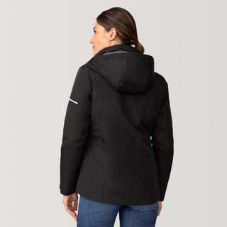 [Olga is 5’9” wearing a size Small.] Woman wearing Free Country Women's Back of Bell 3-in-1 Systems Jacket in black with a full front zipper opening, soft lining, attached hood with adjustable drawcords, and water resistant and wind resistant stretch performance fabric, inner puffer jacket, outer shell for weather, light grey background. Perfect women’s  jacket for fall weather.