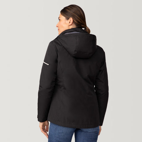 [Olga is 5’9” wearing a size Small.] Woman wearing Free Country Women's Back of Bell 3-in-1 Systems Jacket in black with a full front zipper opening, soft lining, attached hood with adjustable drawcords, and water resistant and wind resistant stretch performance fabric, inner puffer jacket, outer shell for weather, light grey background. Perfect women’s  jacket for fall weather.