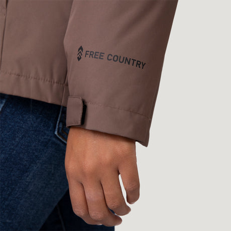 [Shelby is 5’9” wearing a size Small.] Woman wearing Free Country Women's Back of Bell 3-in-1 Systems Jacket in brown with a full front zipper opening, soft lining, attached hood with adjustable drawcords, and water resistant and wind resistant stretch performance fabric, inner puffer jacket, outer shell for weather, light grey background. Perfect women’s  jacket for fall weather.
