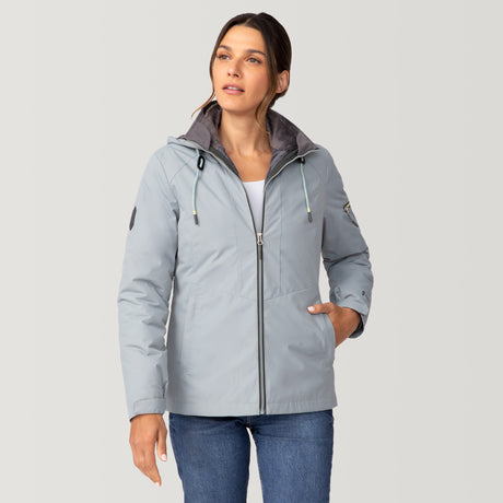 [Olga is 5’9” wearing a size Small.] Woman wearing Free Country Women's Back of Bell 3-in-1 Systems Jacket in light blue with a full front zipper opening, soft lining, attached hood with adjustable drawcords, and water resistant and wind resistant stretch performance fabric, inner puffer jacket, outer shell for weather, light grey background. Perfect women’s  jacket for fall weather.