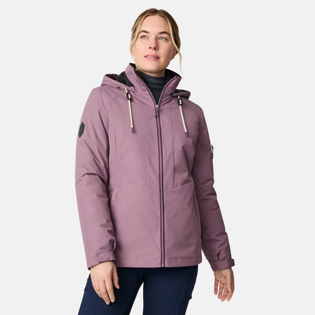 A woman models the Free Country Women's Back of Bell 3-in-1 Systems Jacket in mauve over a black turtleneck, standing against a plain white background with one hand relaxed and the other slightly bent, gazing off to the side.