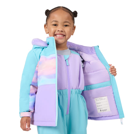 A young girl with her hair in two buns smiles while holding open a light blue and lavender puffer jacket to show the interior lining. The jacket features pastel color-blocked panels in purple, pink, and light blue, with a matching lavender hood and a white interior label.