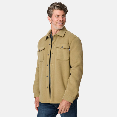 [Kolby is 6'2" wearing size M.] Men’s Free Country tan button-up jacket, sherpa-lined for added warmth, featuring dual flap chest pockets and thick, textured outer fabric—layered over a dark shirt and paired with blue jeans for a rugged, cold-weather look with timeless outdoors appeal.