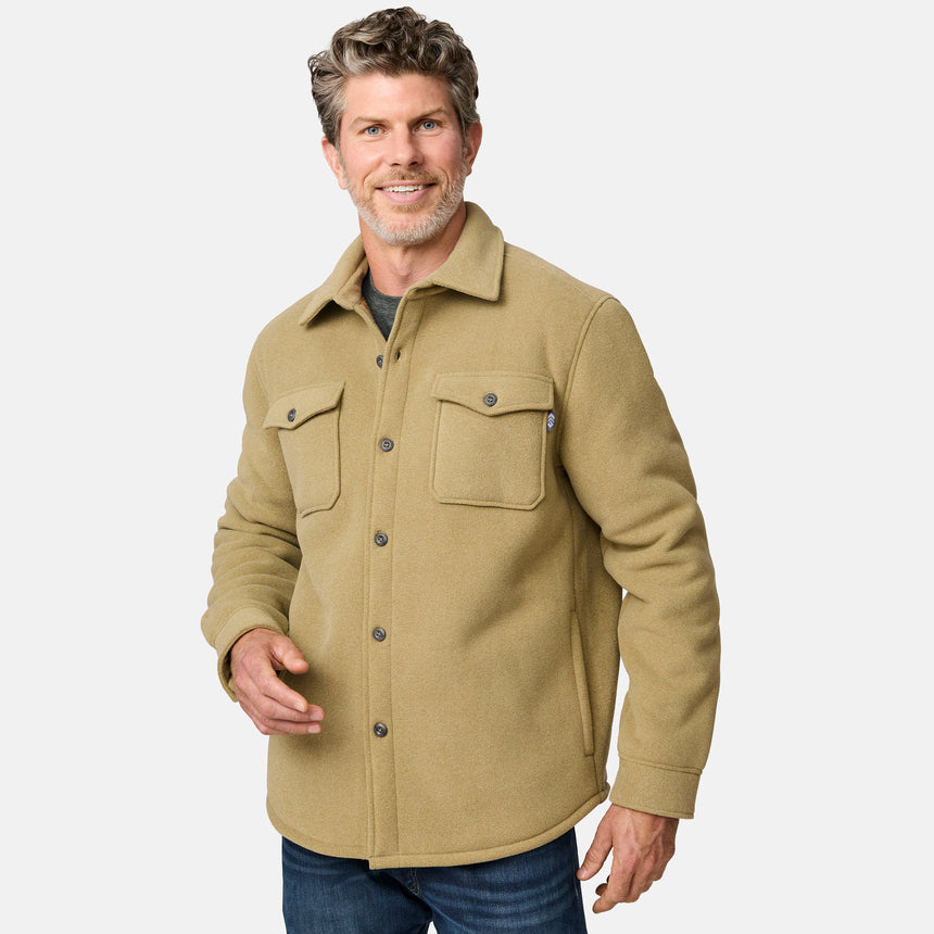 [Kolby is 6'2" wearing size M.] Men’s Free Country tan button-up jacket, sherpa-lined for added warmth, featuring dual flap chest pockets and thick, textured outer fabric—layered over a dark shirt and paired with blue jeans for a rugged, cold-weather look with timeless outdoors appeal.
