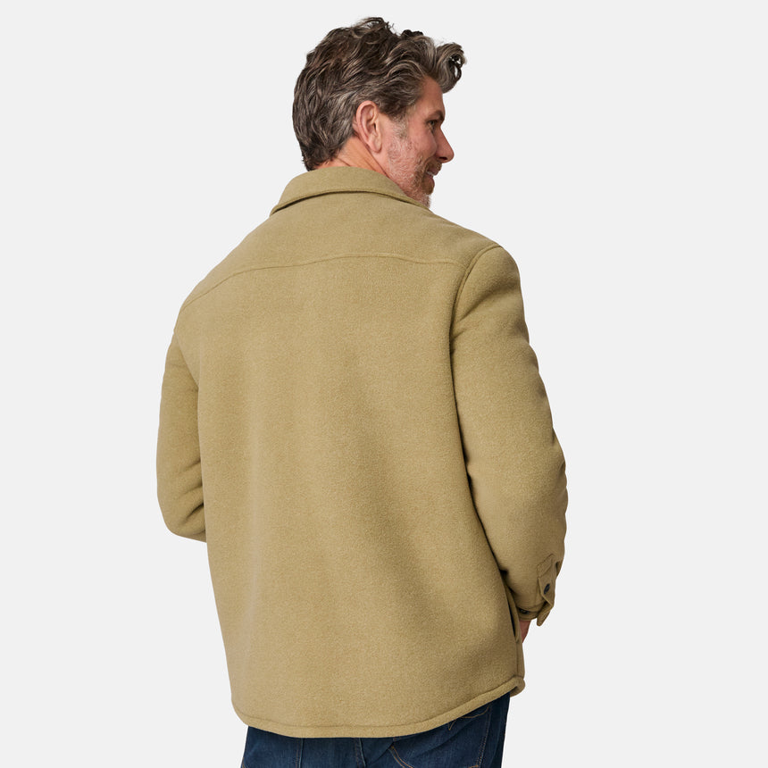 [Kolby is 6'2" wearing size M.] Men’s Free Country tan button-up jacket, sherpa-lined for added warmth, featuring dual flap chest pockets and thick, textured outer fabric—layered over a dark shirt and paired with blue jeans for a rugged, cold-weather look with timeless outdoors appeal.