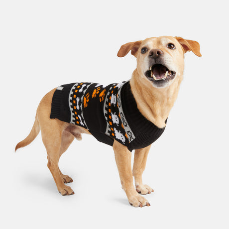 A tan dog wearing the Clearance Dog Halloween Sweater, featuring black fabric with orange, white, and gray patterns, stands on a white background and looks up with its mouth open.