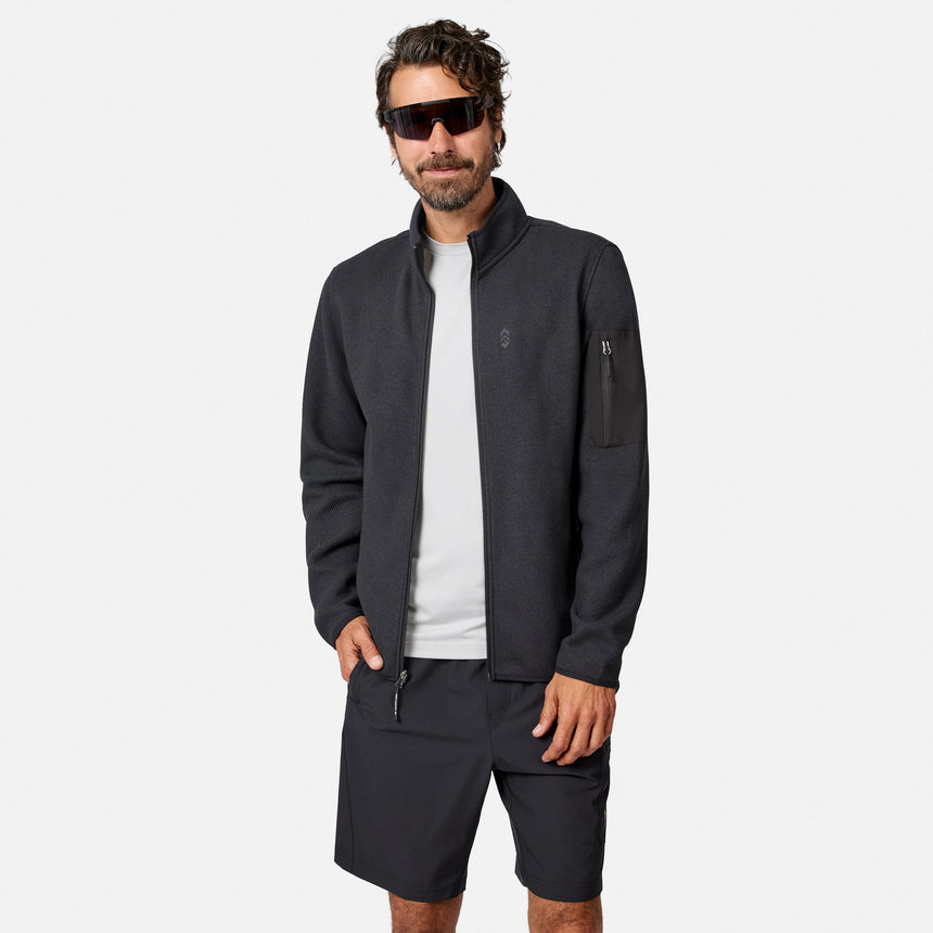 [Model is wearing size M.] A man wearing a dark gray zip-up fleece jacket, matching dark gray shorts, a white t-shirt, and black sunglasses, standing against a light gray studio background.