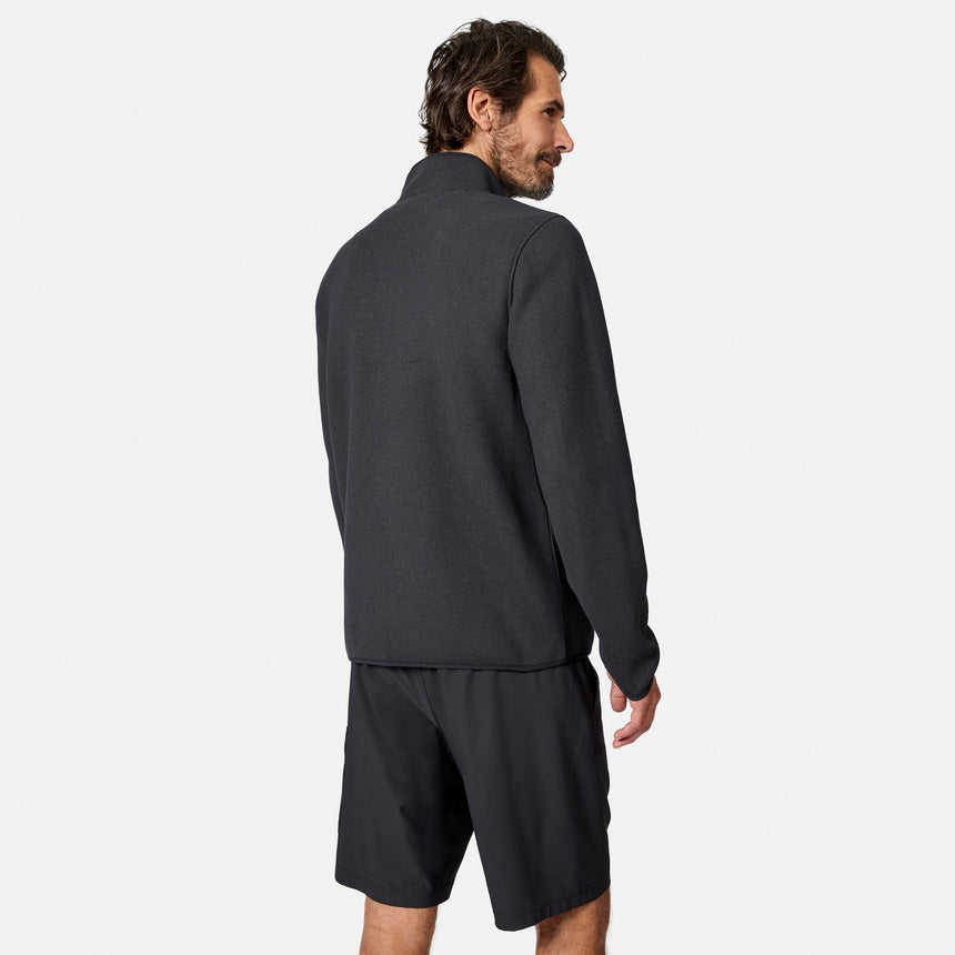 [Model is wearing size M.] A man wearing a dark charcoal gray long-sleeve quarter-zip fleece and matching dark shorts, shown from a three-quarters back view against a light gray studio background.