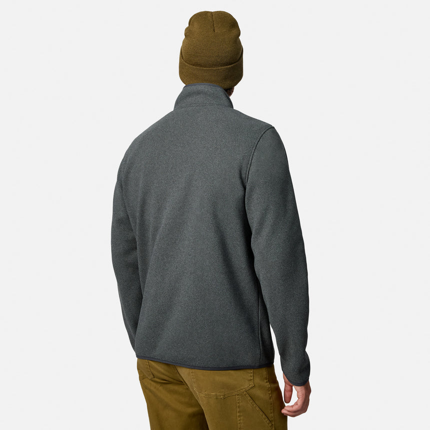 [Model is wearing size M.] A man shown from the back wearing a dark heather gray quarter-zip fleece jacket, a brown knit beanie, and brown pants, against a light gray studio background.