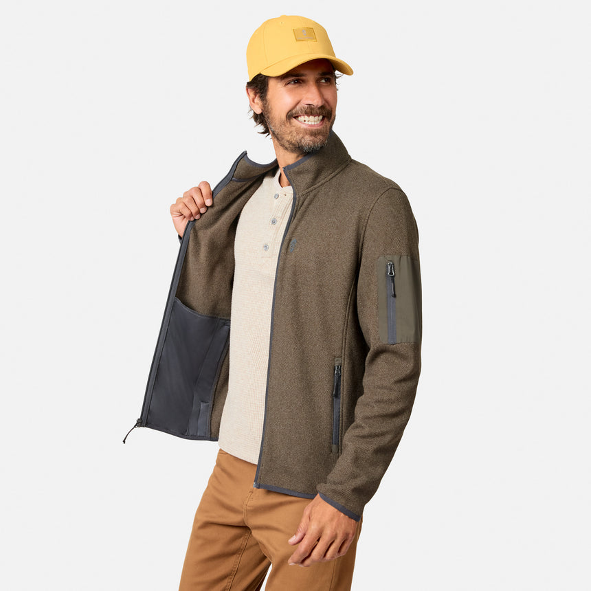 [Model is wearing size M.] A man wearing a brown fleece jacket with a dark gray interior lining, a beige henley shirt, brown pants, and a yellow cap, shown against a light gray background.