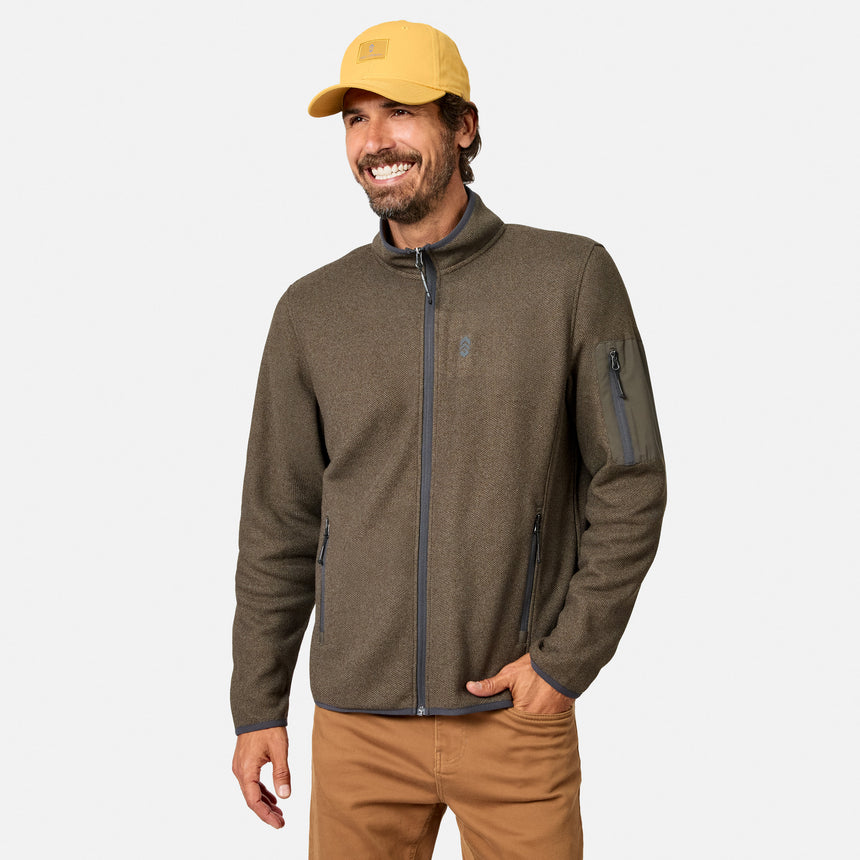 [Model is wearing size M.] A man wearing a brown fleece jacket with dark gray zipper details, a yellow baseball cap, and tan pants, standing against a light gray studio background.