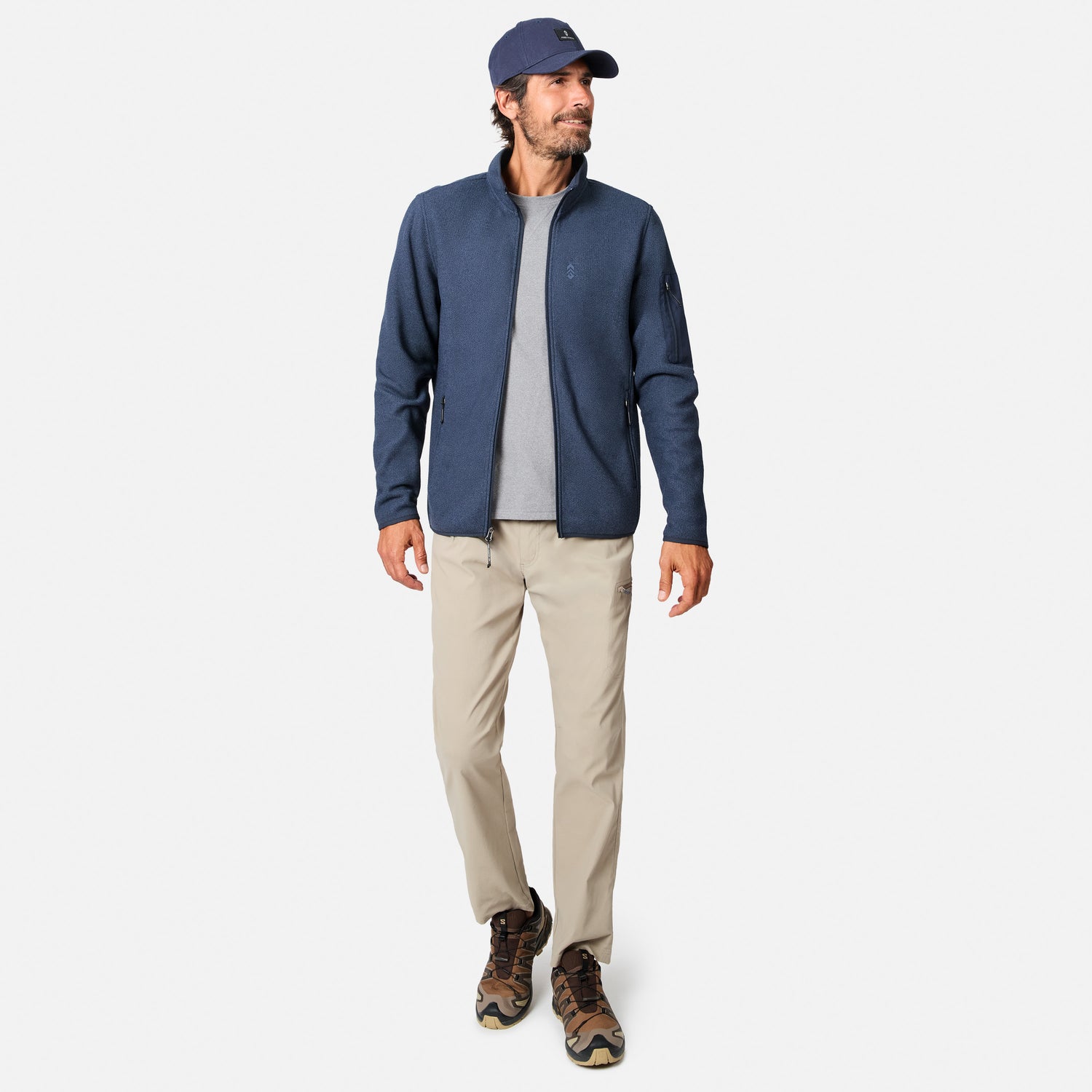 [Model is wearing size M.] A man modeling a navy blue quarter-zip fleece jacket, worn over a gray t-shirt with beige pants and brown hiking boots, on a light gray background.