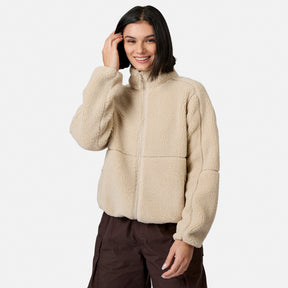 [Model is wearing size S.] A woman wearing a beige sherpa fleece zip-up jacket and dark brown cargo pants, standing against a light gray studio background.