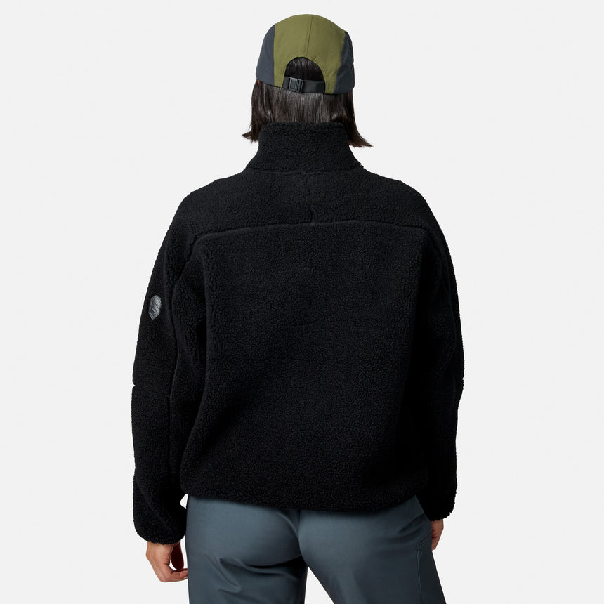 [Model is wearing size S.] A person shown from the back wearing a black fleece quarter-zip jacket, gray pants, and a green and gray baseball cap against a light gray studio background.