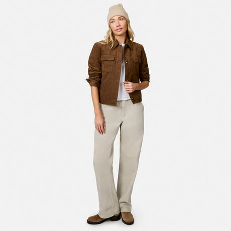 [Model is wearing size S.] A woman modeling a brown suede utility jacket, beige wide-leg trousers, a white t-shirt, brown suede loafers, and a beige beanie against a light gray studio background.