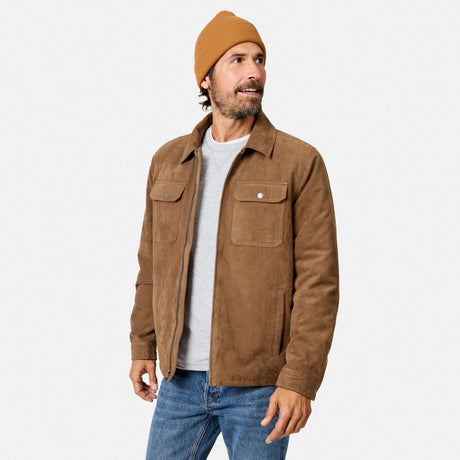[Model is wearing size M.] A man wearing a brown suede jacket, a tan beanie, a light gray t-shirt, and blue jeans, standing against a light gray studio background.