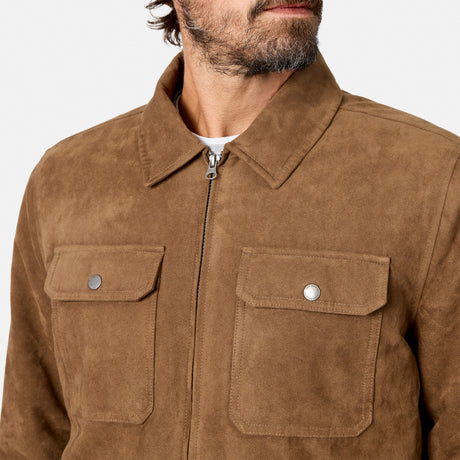 [Model is wearing size M.] A close-up of a man wearing a brown suede jacket with a zippered front, two flap chest pockets with silver snap buttons, and a pointed collar, against a light gray background.