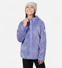 A girl smiles while wearing a grey beanie and a purple Free Country Girls’ Braided Butter Pile® Jacket, featuring a textured braided pattern and a zip-up front.