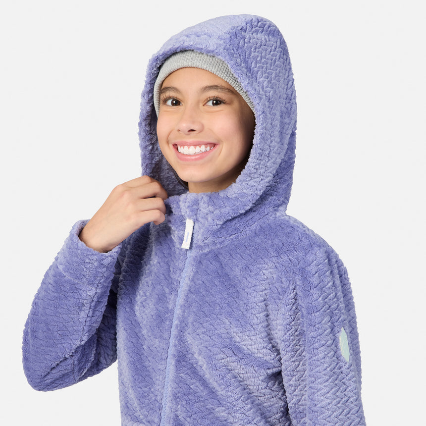 A girl smiling while wearing a lavender textured Girls’ Braided Butter Pile® Jacket and a grey beanie.