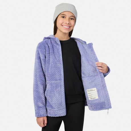 A girl wearing a grey beanie and a purple, textured Girls’ Braided Butter Pile® Jacket, showing the interior name tag label of the fleece hooded garment.