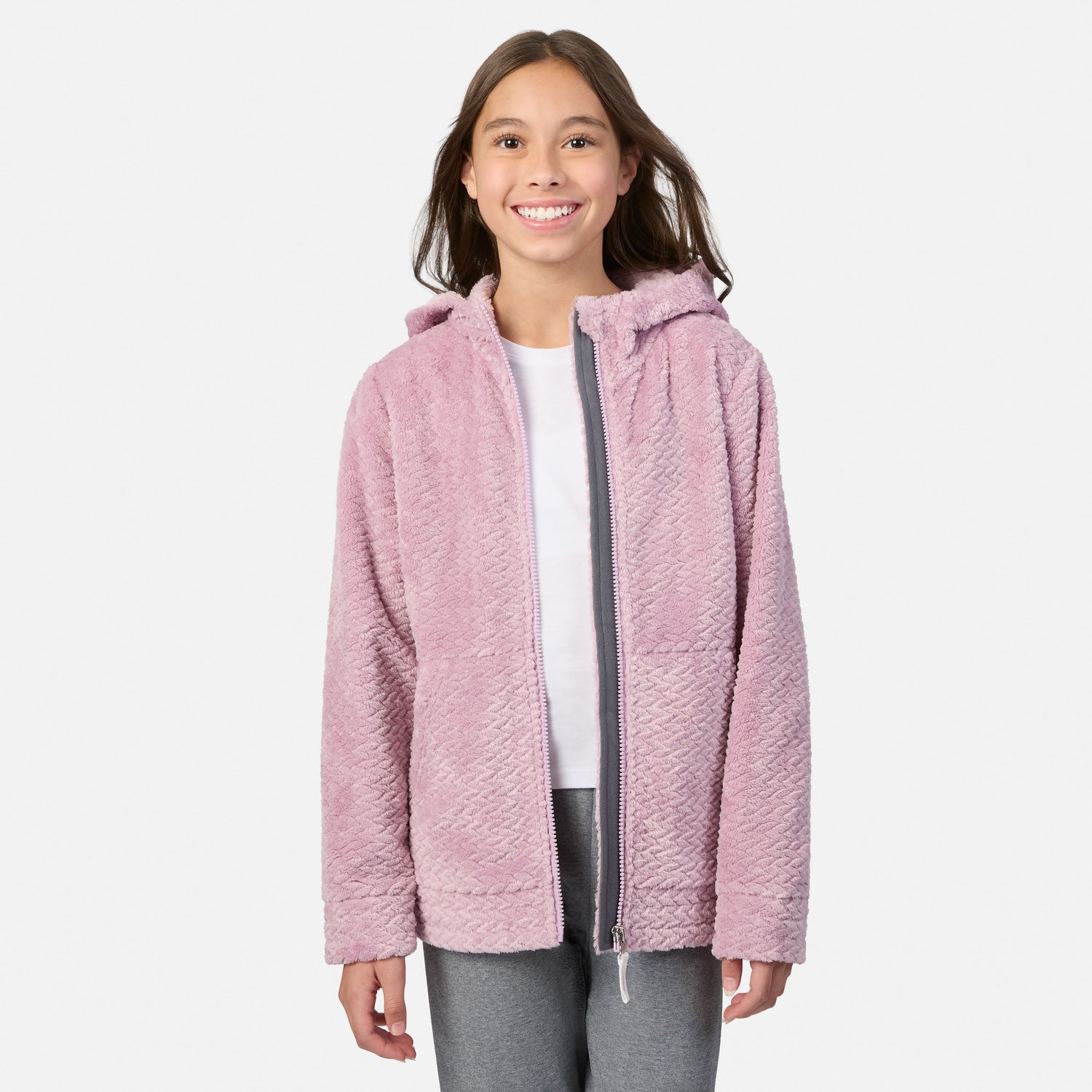 A girl wearing a pink Girls’ Braided Butter Pile® Jacket with a hooded design and a gray zipper over a white shirt.