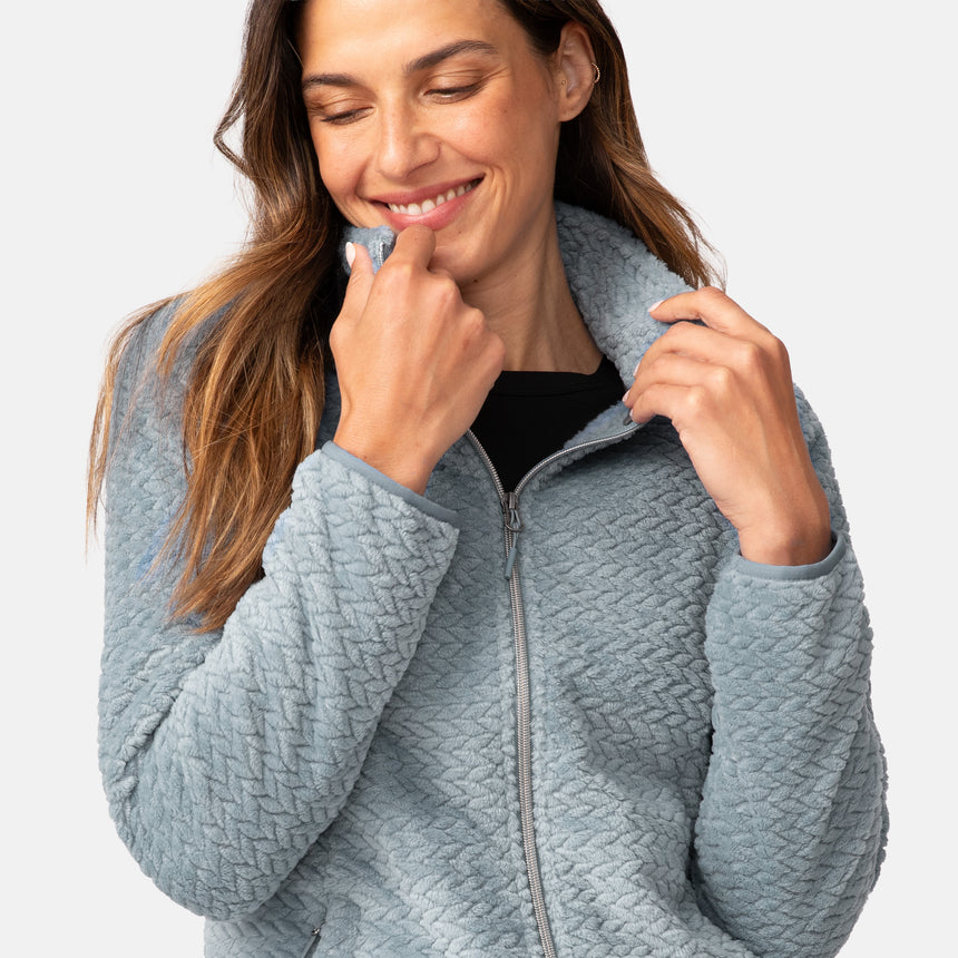 Woman wearing a green quilted fleece jacket on a white background