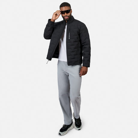 [Model is wearing size M.] A man modeling a black puffer jacket over a white t-shirt, paired with light gray sweatpants and black sneakers, against a plain light gray background.