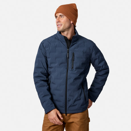 [Model is wearing size M.] A man wearing a navy blue puffer jacket, a rust-orange beanie, and brown pants, standing against a light gray studio background.