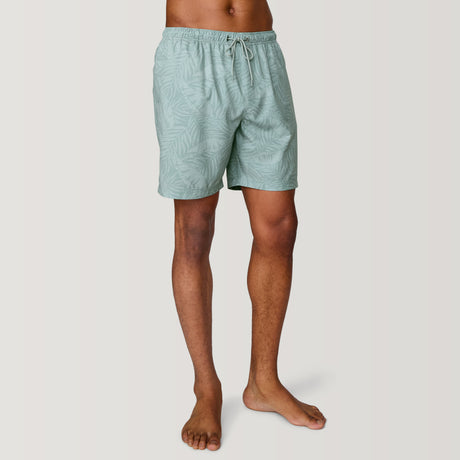 A person stands barefoot in Clearance Men's Palm Heaven Swim Short, light green with a subtle leaf print. Made from recycled polyester, featuring an elastic waistband and drawstring, these UPF 50+ shorts are shown on a plain white background, upper body not fully visible.